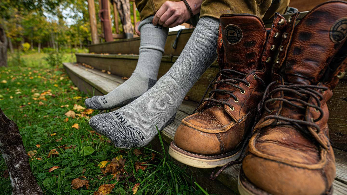 closeup of man putting on minus33 merino wool expedition mountaineer socks
