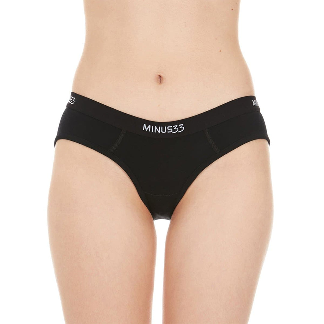 A woman models a pair of super soft merino wool bikini brief underwear. Light and breathable, these briefs feature a 1-inch woven sport elastic band, and high cut leg openings for a better range of movement. #color_black