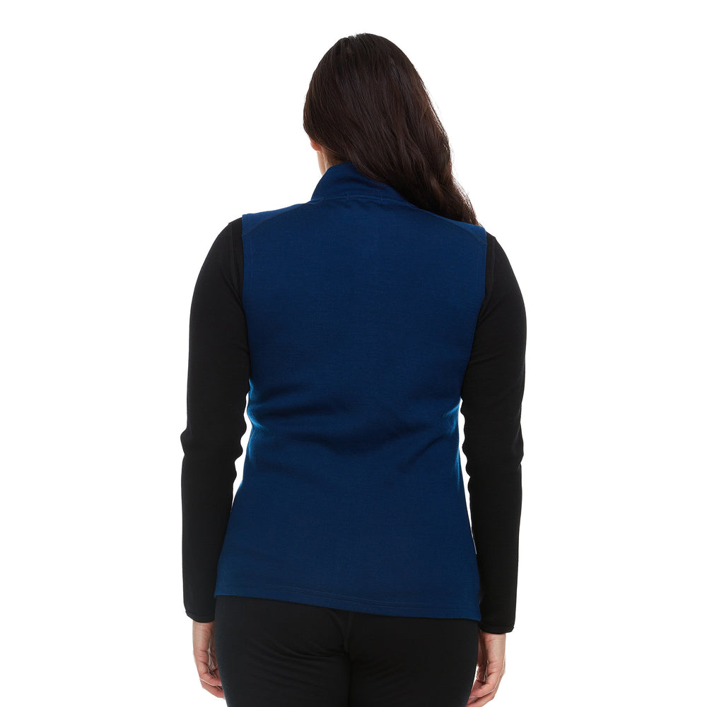 A woman models a hundred percent merino wool heavyweight full zip vest. This outer layer features a two and a half inch mock neck collar and two zippered pockets. #color_navy