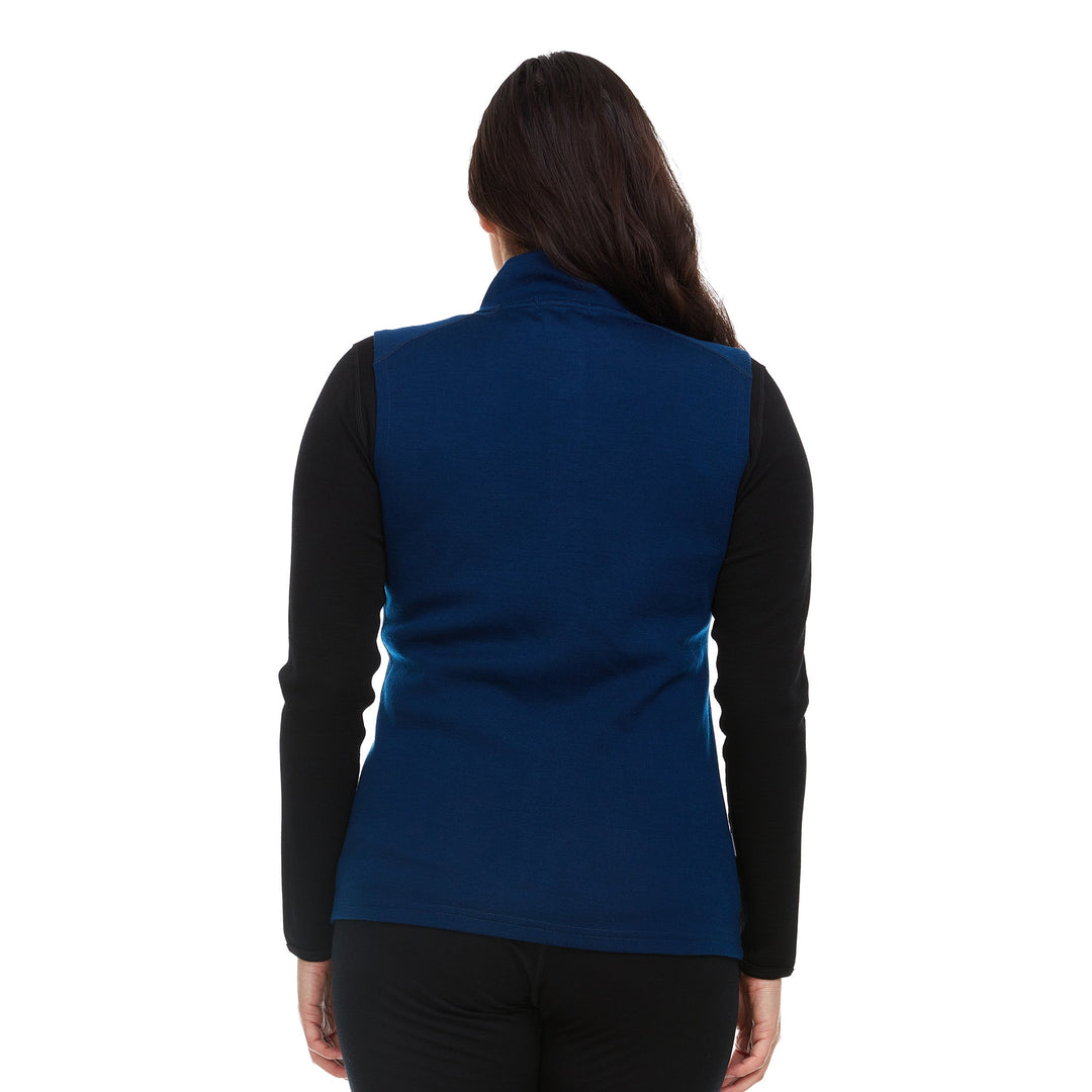 A woman models a hundred percent merino wool heavyweight full zip vest. This outer layer features a two and a half inch mock neck collar and two zippered pockets. #color_navy