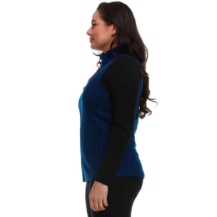 A woman models a hundred percent merino wool heavyweight full zip vest. This outer layer features a two and a half inch mock neck collar and two zippered pockets. #color_navy